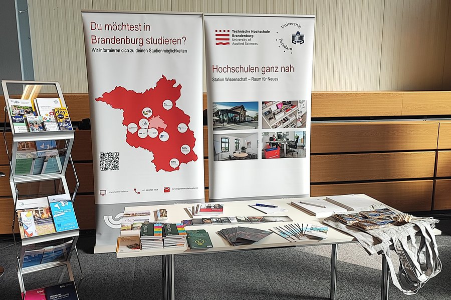 Messestand mit Tisch, Prospektständer und Rückwand