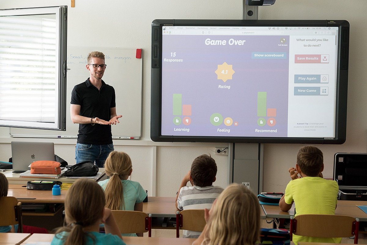 Lehrer steht vor der Klasse neben Leinwand
